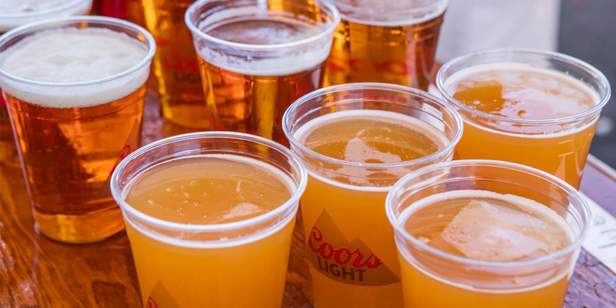 Table with plastic cups full of Blue Moon and Coors Light