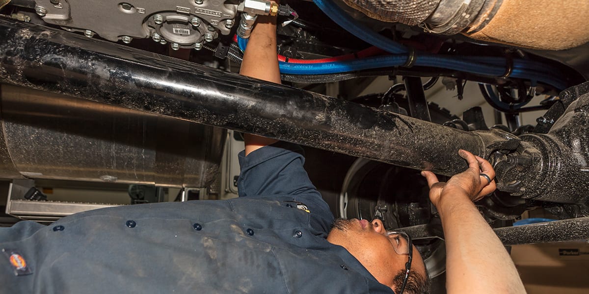 Man working underneath of truck to fix it