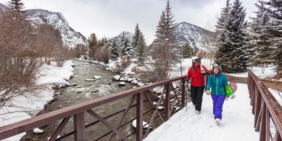 Skier and snowboarder walking on bridge in Frisco