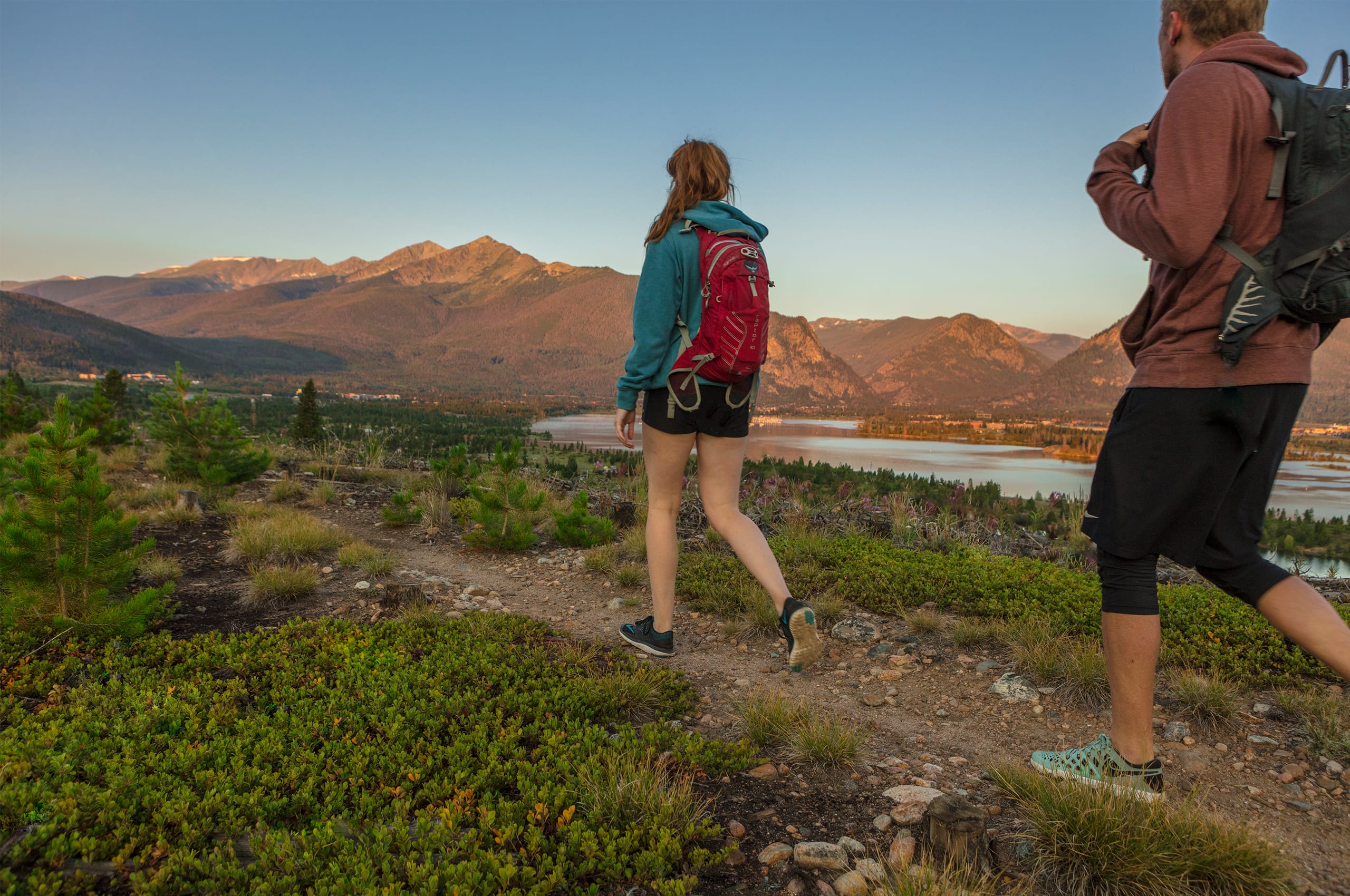 Man and woman hiking on a dirt trail near Dillon Reservoir, peak one in the background
