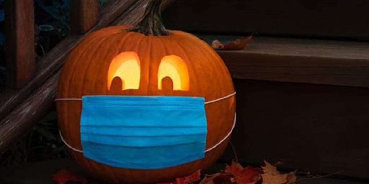 Pumpkin with glowing eyes and a blue mask sitting on a set of stairs