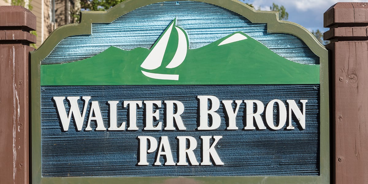 Walter Byron Park sign- wood with white lettering, green mountains, and a sail boat