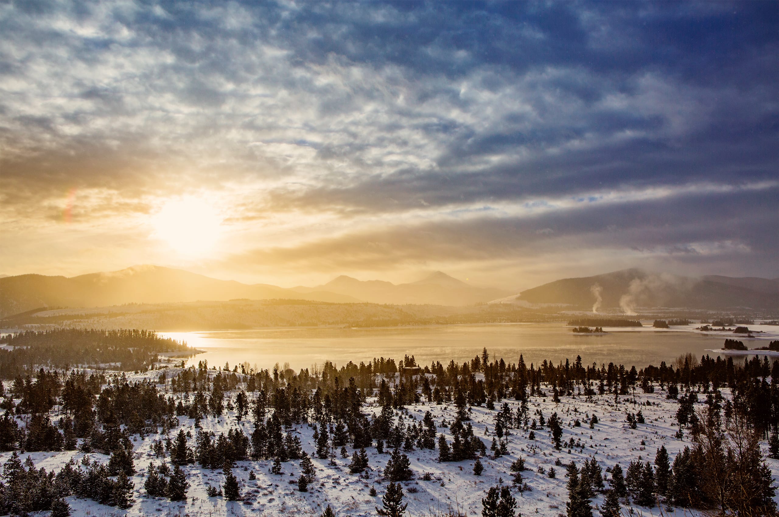 Dillon Reservoir with snow and sun shining through the clouds