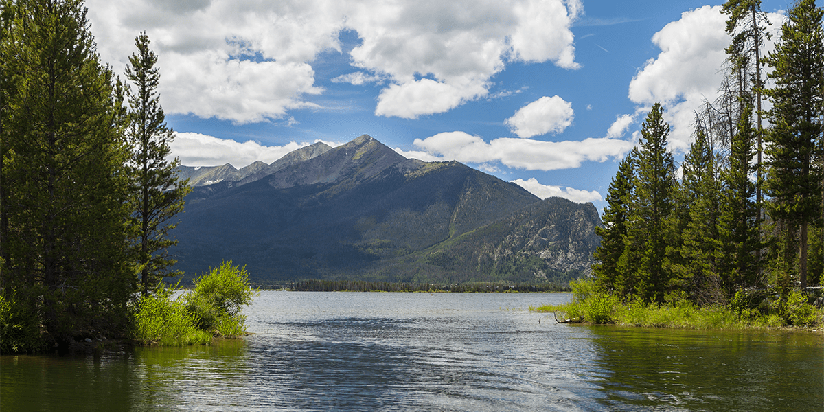 View of Tenmile Range from Lake Dillon with trees framing the water