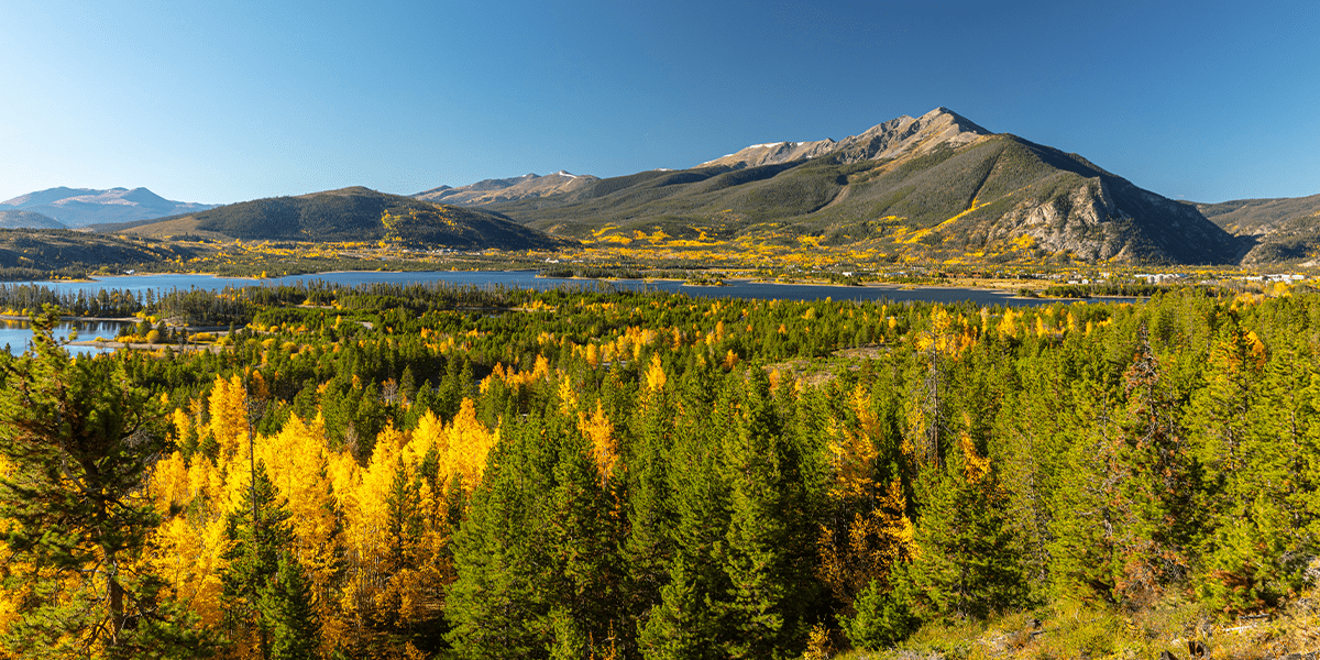 Scenic image of yellow and green aspens with Lake Dillon and Peak One in the background
