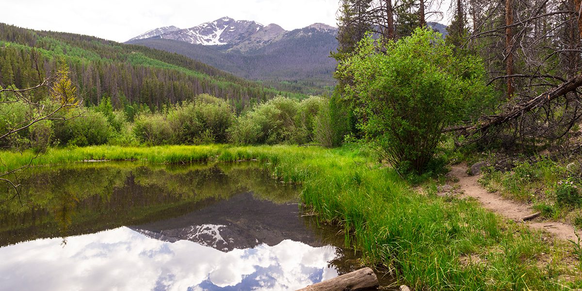 Rainbow Lake with a trail and Peak One in the background