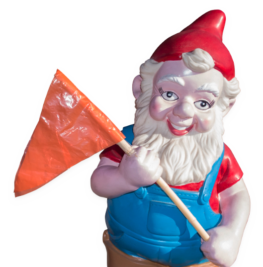 A plastic gnome dressed in a red hat and blue overalls carrying an orange construction flag