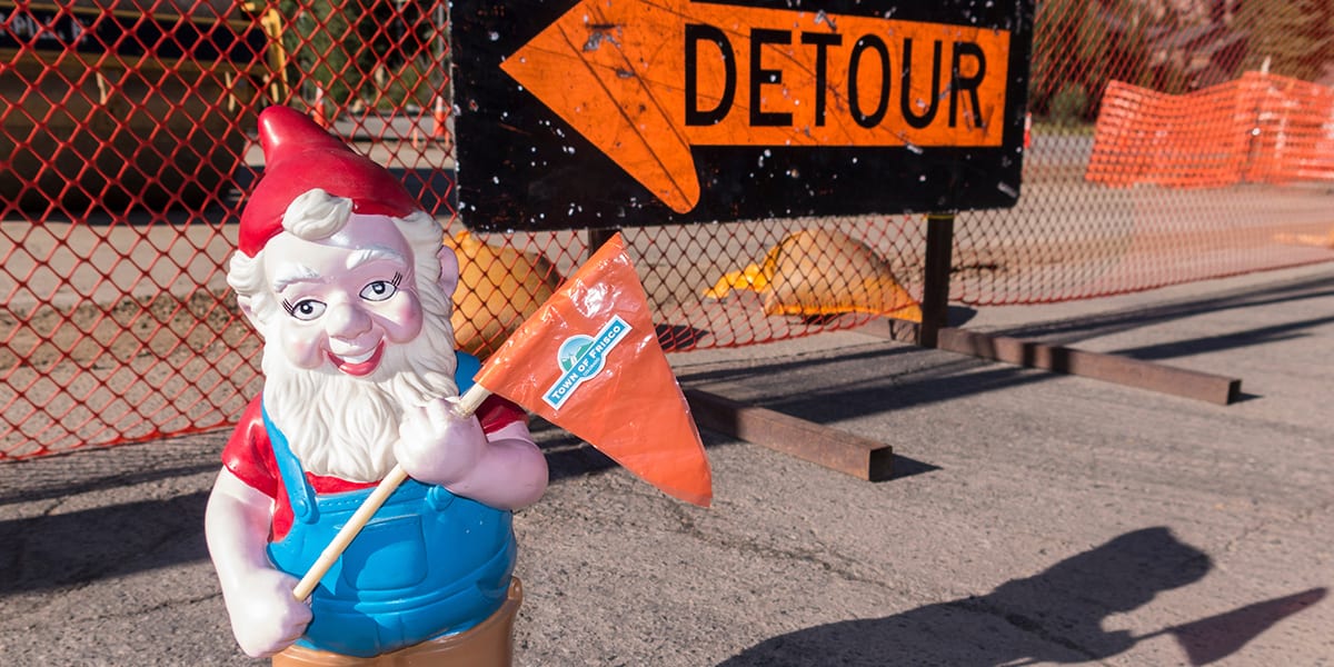 Jerome the Construction Gnome standing in front of an orange detour sign