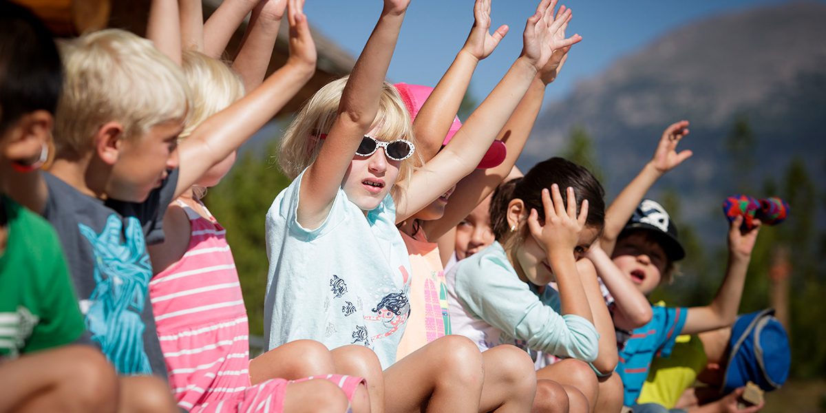 Kids wearing sunglasses raising their hands as to answer questions at a field trip