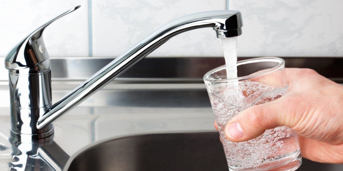 person getting drinking water from the tap