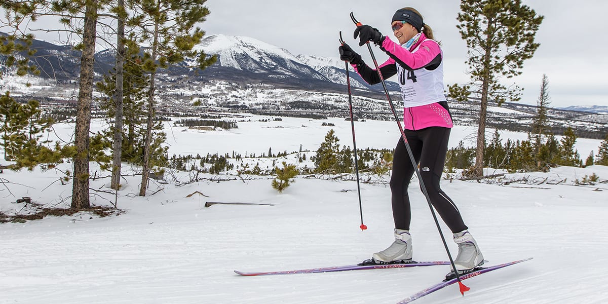 A woman in a pink snow suit cross-country skis near the Dillon Reservoir
