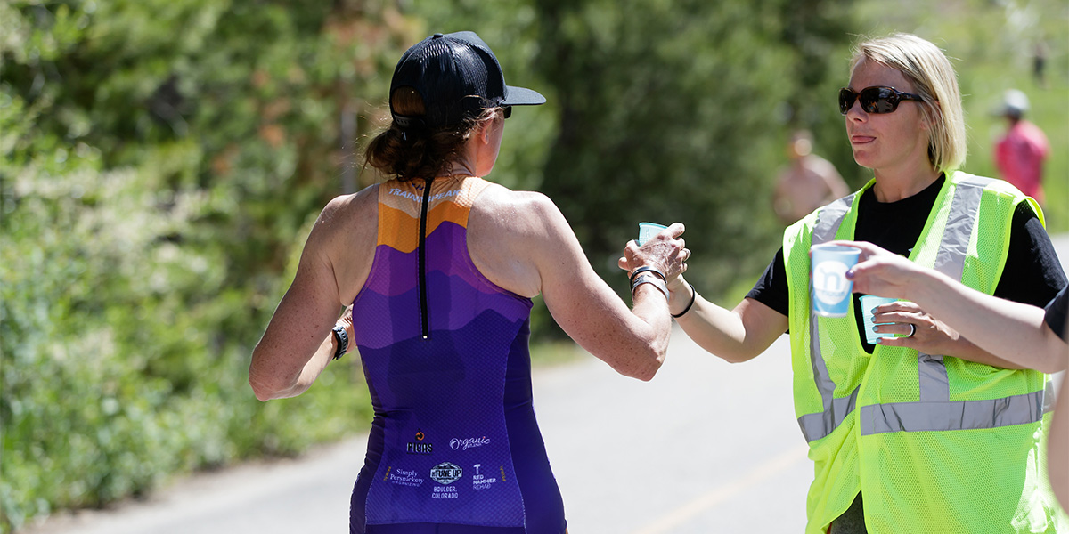 Volunteer handing runner cup of water at Frisco Triathlon