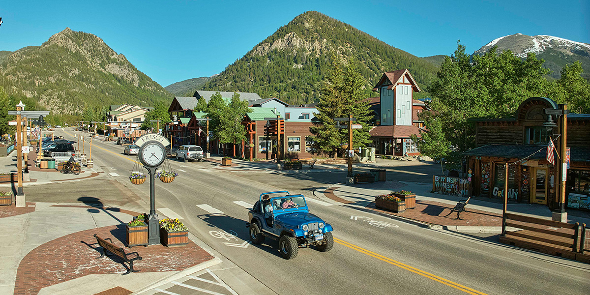 Blue Jeep driving on Frisco Main Street in summer next to Frisco clock