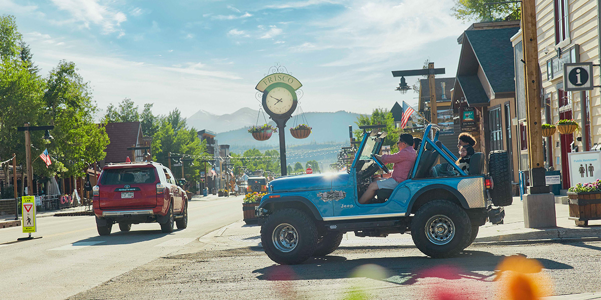Blue Jeep turning on to Main Street at 3rd Avenue with Frisco clock in background