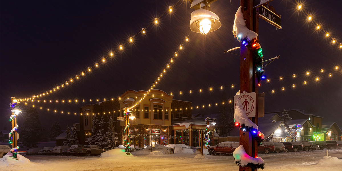 Light pole and intersection at Main Street and Fourth Avenue at night in the winter with snow