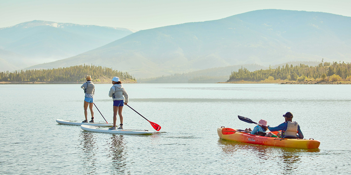 Family of four stand up paddle boarding and kayaking on Dillon Reservoir